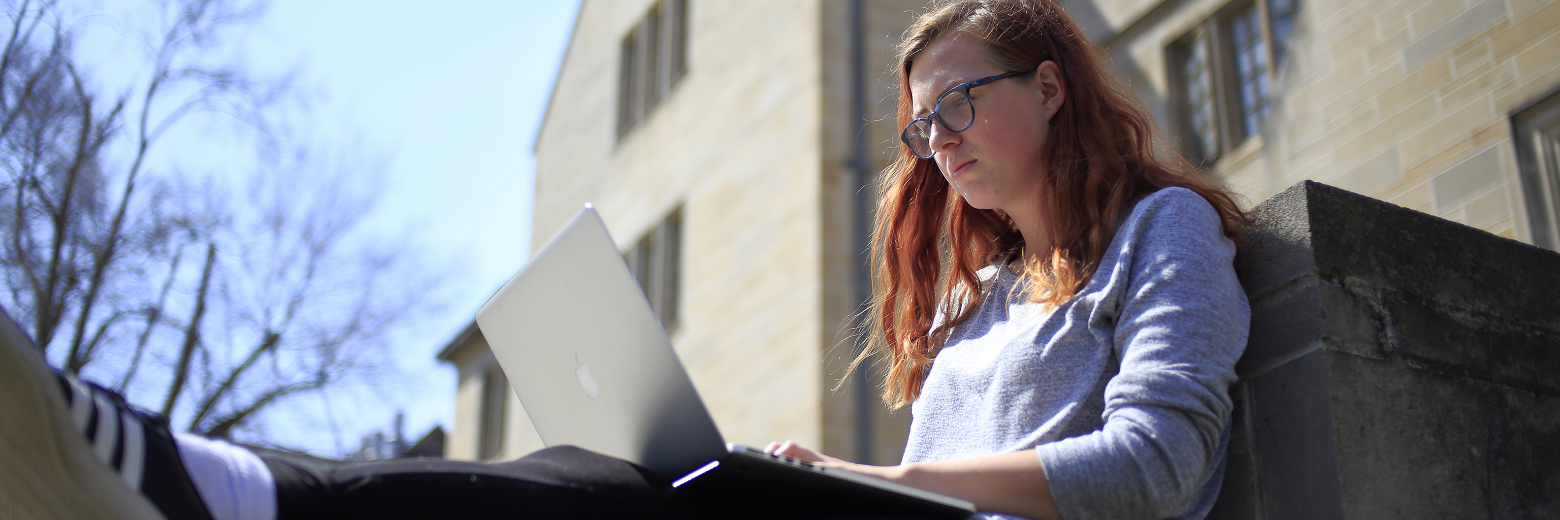 Indiana University student uses laptop outside an Indiana University Bloomington campus building.