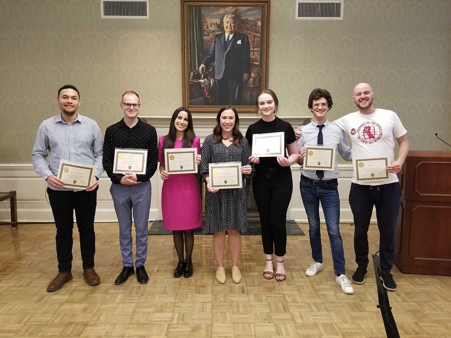 A group of graduate students pose with their recently earned award certificates.