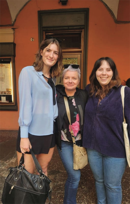Three people pose together outside of a restaurant.
