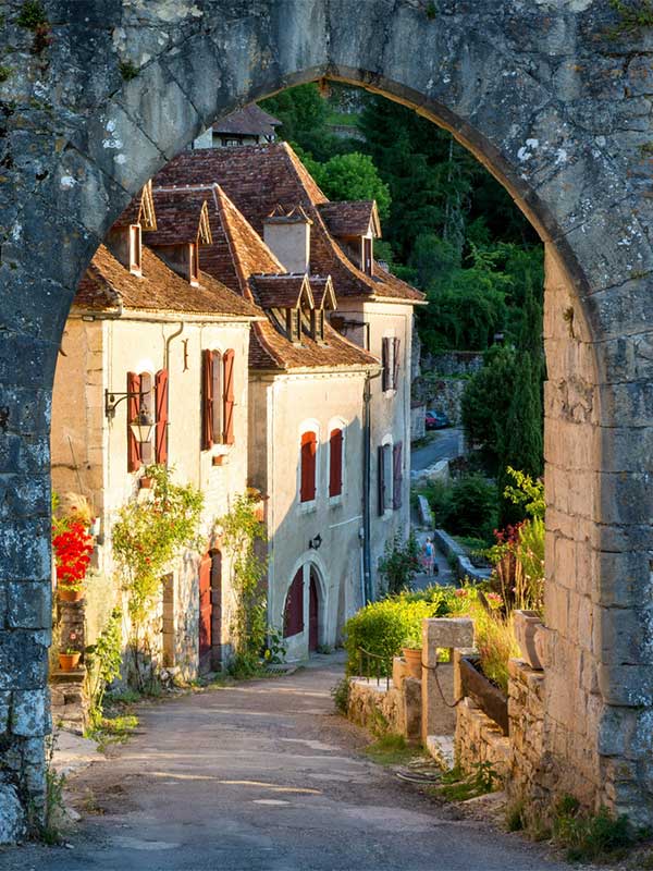 A stone archway frames a sloping street.