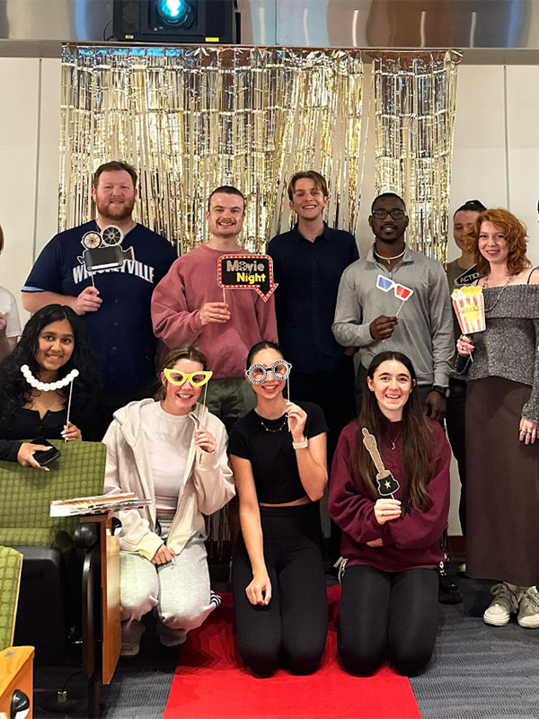 Students post with fake glasses and Oscar trophies at French movie night.